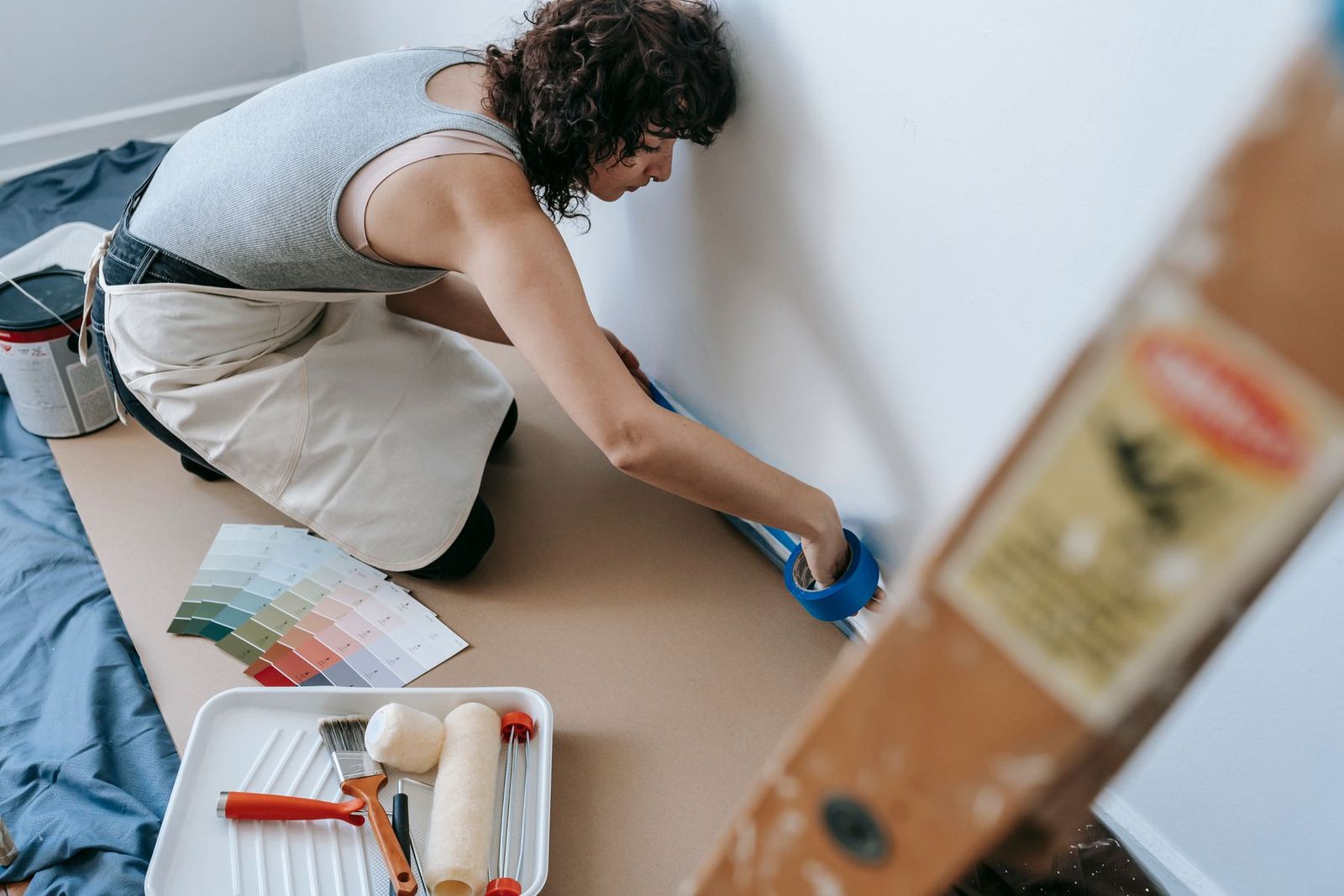 Frau klebt mit blauem Malerband in einer modernen Wohnung ab
