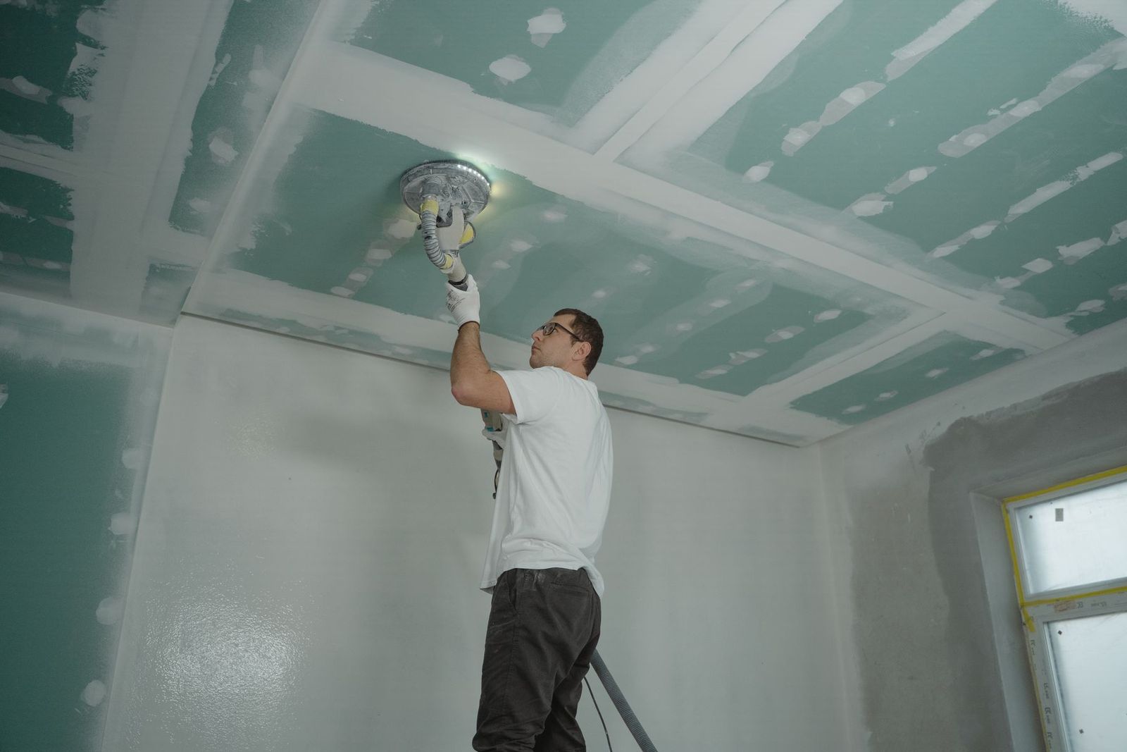 Handwerker schleift eine Zimmerdecke